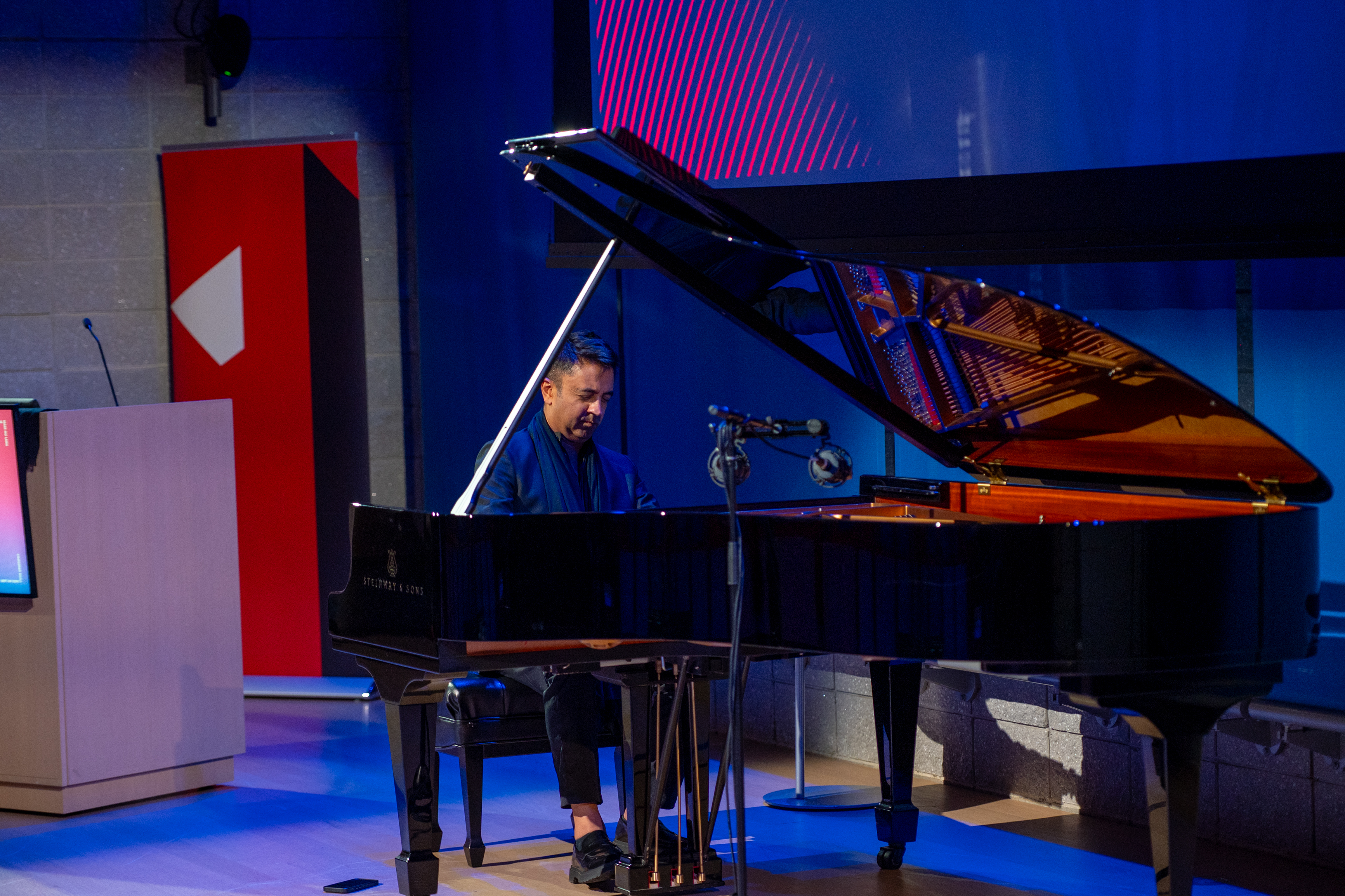Photo of Vijay Iyer playing the piano under at the Forever War and the First Amendment symposium